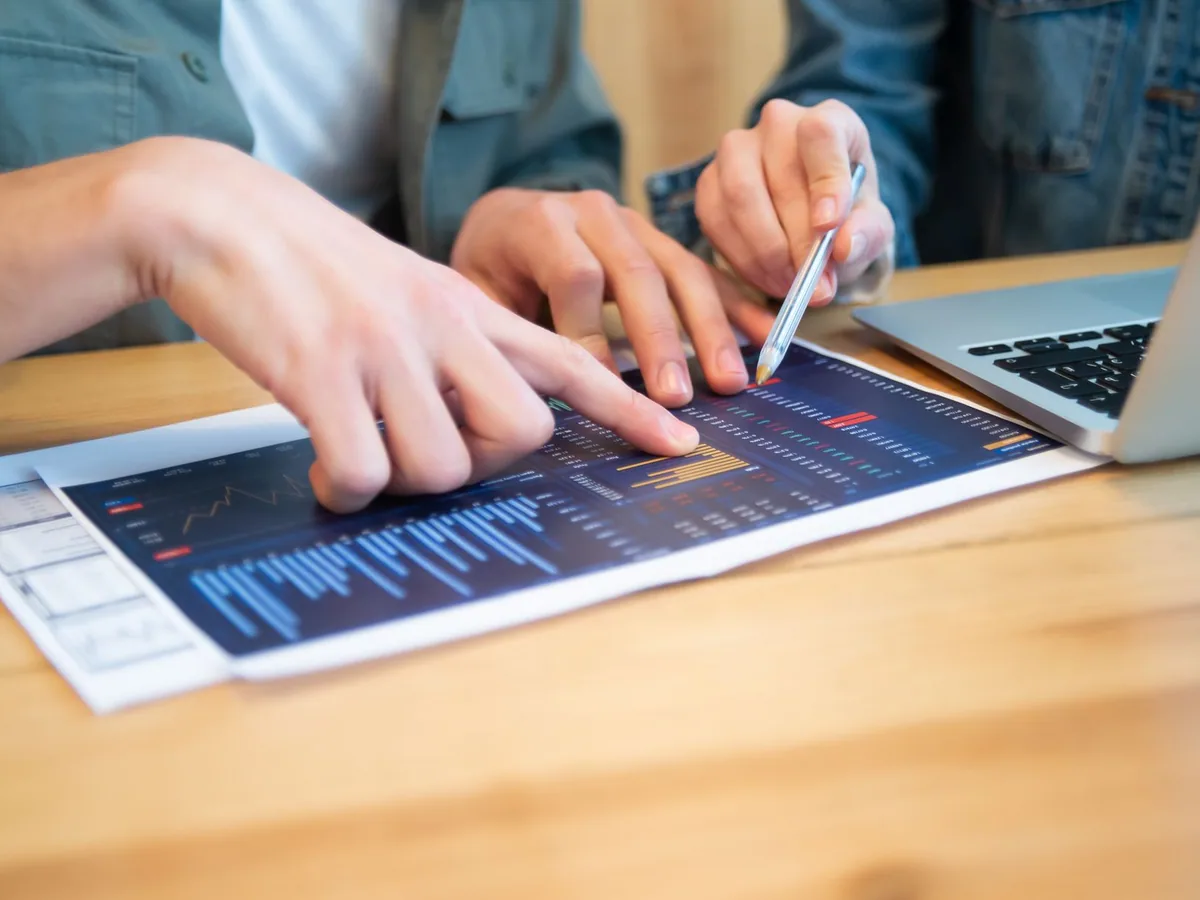 Illustrative stock photograph by Kampus Production / Pexels Hands pointing to business charts beside a laptop